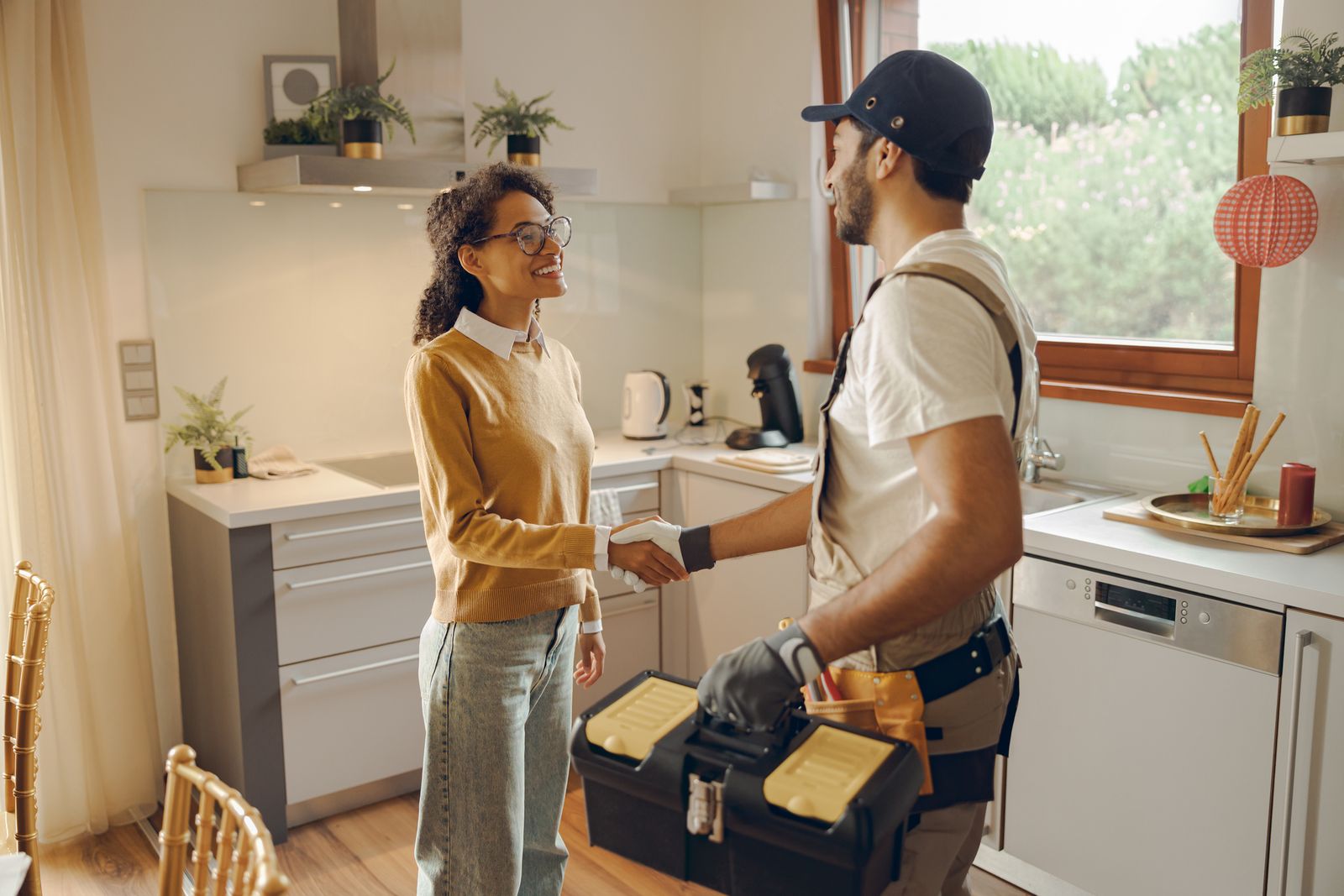 A homeowner welcoming a home service technician into her kitchen